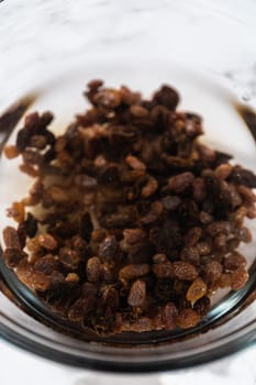 Soaking dried raisins in hot water to baking mini Easter bread kulich.