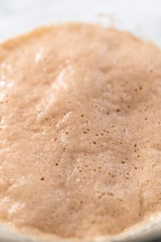 Activating dry yeast in a glass mixing bowl to bake mini Easter bread kulich.