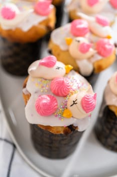 Freshly baked mini Easter bread kulich with lemon glaze, decorated with sprinkles and meringue bird-shaped cookies.