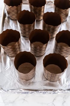 Scooping bread dough into paper liners to bake mini Easter bread kulich.