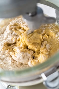 Mixing ingredients in kitchen mixer to bake mini Easter bread kulich.