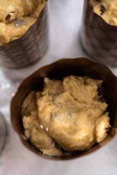 Rising dough in paper liners to bake mini Easter bread kulich.