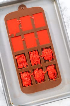 Filling silicone mold with red and blue melted chocolate to make chocolate stars for patriotic lemon cupcakes.