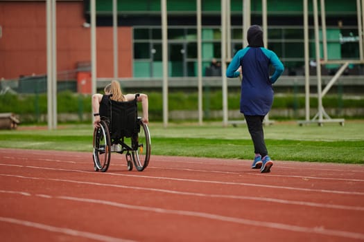 A Muslim woman in a burqa running together with a woman in a wheelchair on the marathon course, preparing for future competitions