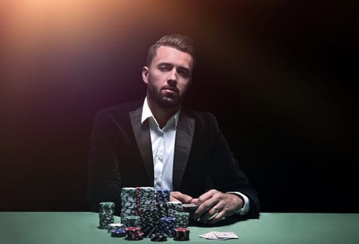 Young man sitting at the poker table with his chips and cards in front of him