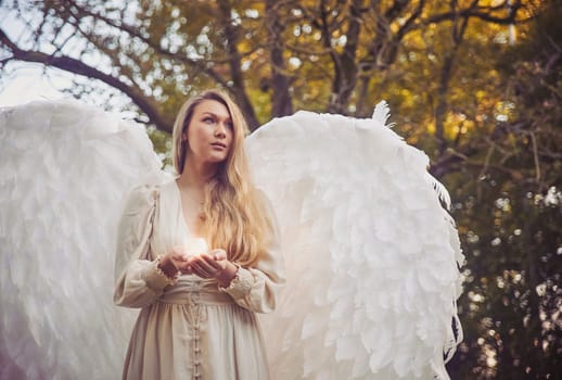 Girl angel with a candle in the evening forest.