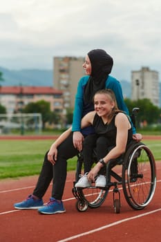 A Muslim woman wearing a burqa resting with a woman with disability after a hard training session on the marathon course.