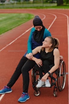 A Muslim woman wearing a burqa resting with a woman with disability after a hard training session on the marathon course.