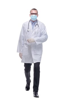 Walking young male doctor wearing glasses and surgical mask. Full length studio shot isolated on white.