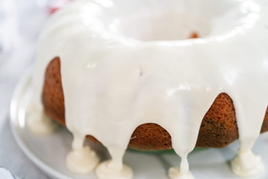 Glazing freshly baked bundt cake with vanilla glaze.