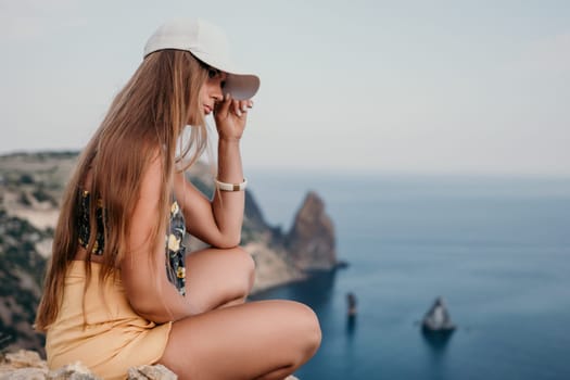 Woman travel sea. Happy tourist taking picture outdoors for memories. Woman traveler looks at the edge of the cliff on the sea bay of mountains, sharing travel adventure journey.