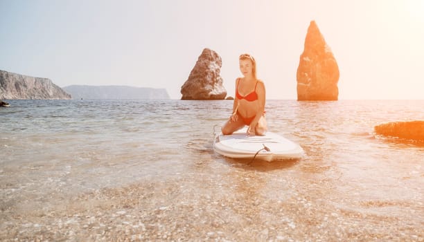 Close up shot of beautiful young caucasian woman with black hair and freckles looking at camera and smiling. Cute woman portrait in a pink bikini posing on a volcanic rock high above the sea