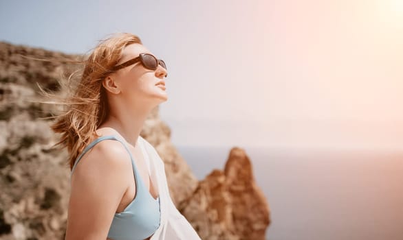 Woman travel sea. Young Happy woman in a long red dress posing on a beach near the sea on background of volcanic rocks, like in Iceland, sharing travel adventure journey