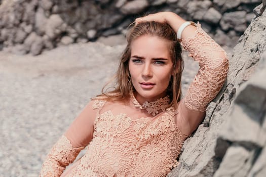 Woman travel sea. Young Happy woman in a long red dress posing on a beach near the sea on background of volcanic rocks, like in Iceland, sharing travel adventure journey