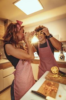 Happy young couple enjoys and having fun in making and having healthy meal together at their home kitchen.