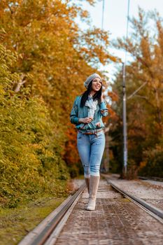 Beautiful young pensive woman enjoying in autumn colors  walking in the city park, looking away.