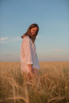 Woman in the yellow field of wheat, beauty summer sunset