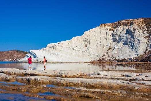 A couple looking and admires the Scala dei Turchi. A fascinating limestone rock steep on an amazing sea in Realmonte, Agrigento. Sicily