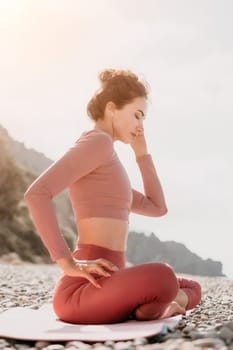 Young woman with long hair in white swimsuit and boho style braclets practicing outdoors on yoga mat by the sea on a sunset. Women's yoga fitness routine. Healthy lifestyle, harmony and meditation