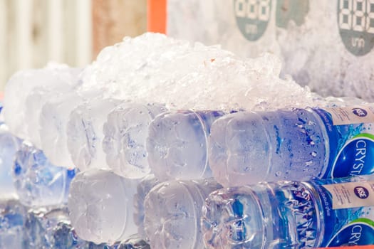 The ice cubes are on a bottle of water to cool.