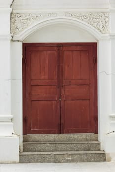 Old brown wood doors on white walls are closed.