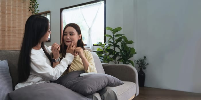 Asian homosexual couple of lesbian woman sitting on couch in living room excessive manifestation of feelings and emotions of the period of love.