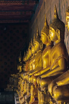 Golden Buddha statue on the pedestal with old walls