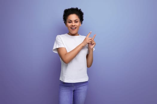young brunette woman with afro hair in a white t-shirt shows her hands on an empty space for a mockup.