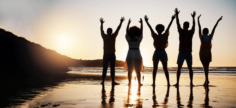 Beach, celebration and back of friends at sunset with arms up for freedom, fun and travel success. Ocean, silhouette and rear view of people celebrating journey, adventure and summer vacation in Bali.