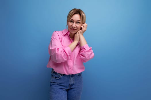 stylish young blond businesswoman in pink shirt and jeans on studio background with copy space.