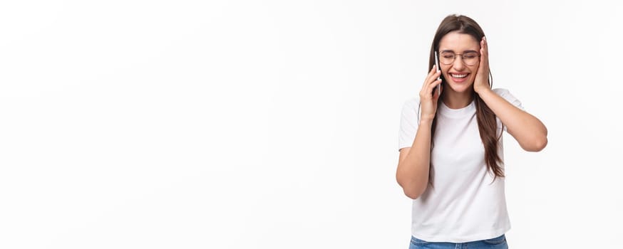 Communication, technology and lifestyle concept. Portrait of excited and happy, overwhelmed young caucasian woman receive excellent news, smiling and laughing, talking on mobile phone.