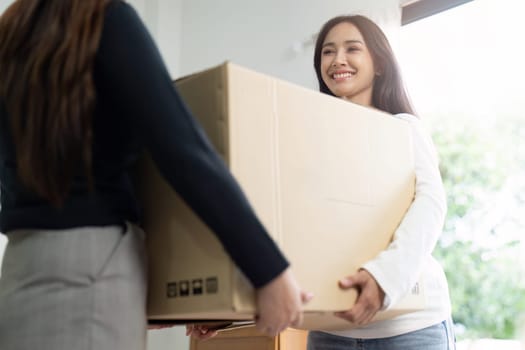 Young woman couple smiling happy and moving box together at new home. Homosexual-LGBTQ concept.