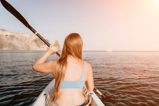 Woman in kayak back view. Happy young woman with long hair floating in transparent kayak on the crystal clear sea. Summer holiday vacation and cheerful female people relaxing having fun on the boat