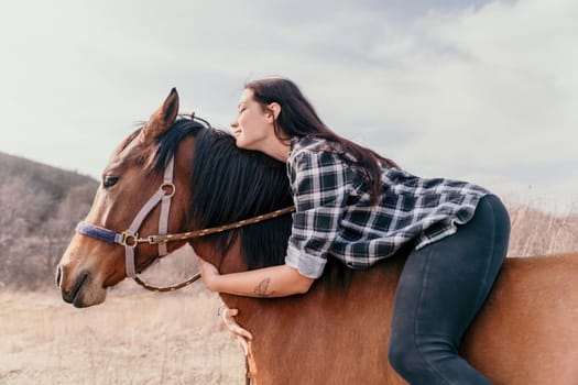 Cute happy young woman with horse. Rider female drives her horse in nature on evening sunset light background. Concept of outdoor riding, sports and recreation.