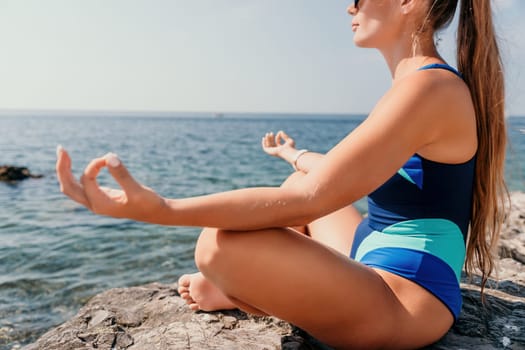 Woman sea yoga. Back view of free calm happy satisfied woman with long hair standing on top rock with yoga position against of sky by the sea. Healthy lifestyle outdoors in nature, fitness concept.