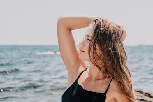 Woman travel sea. Young Happy woman in a long red dress posing on a beach near the sea on background of volcanic rocks, like in Iceland, sharing travel adventure journey