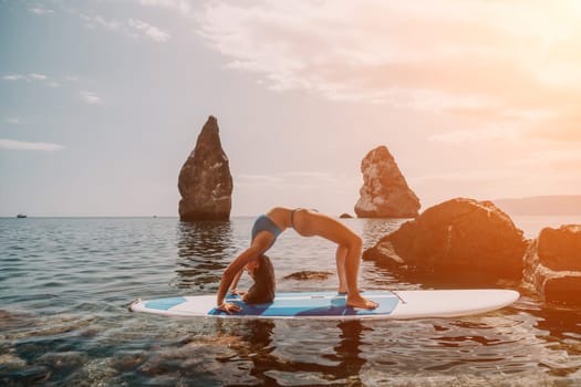 Woman sup yoga. Middle age sporty woman practising yoga pilates on paddle sup surfboard. Female stretching doing workout on sea water. Modern individual hipster outdoor summer sport activity