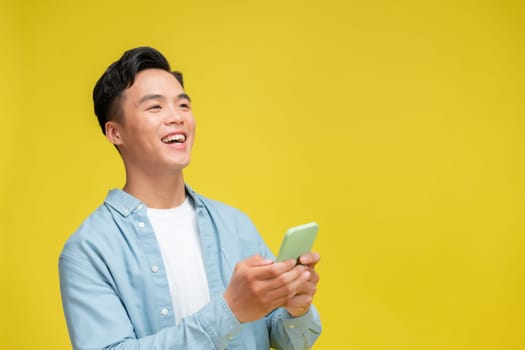 Shocked young Asian man looking at mobile phone screen reacting to online news with opened mouth