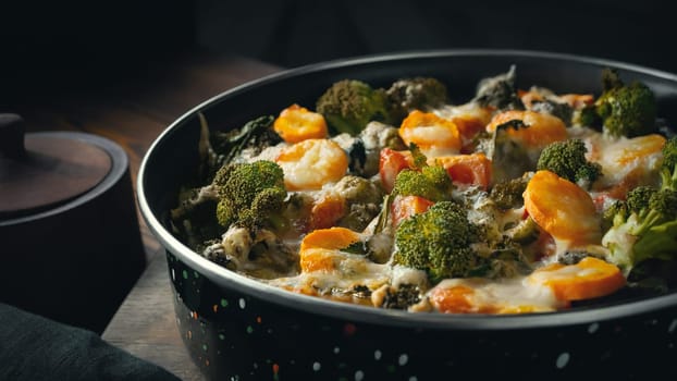 Gratin with broccoli, carrots and cheese baked in the oven on a dark wooden table.
