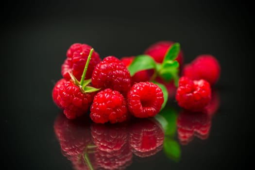 Ripe red raspberries closeup, isolated on black background.