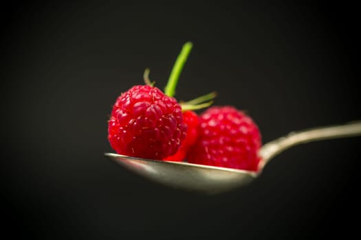 Ripe red raspberries closeup, isolated on black background.