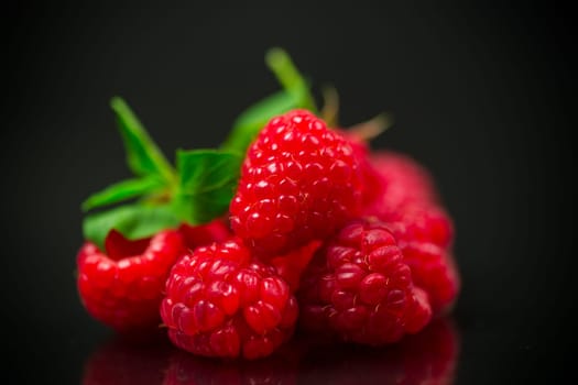 Ripe red raspberries closeup, isolated on black background.