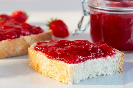 Wheat bread toasts with spread strawberry jam on the table.