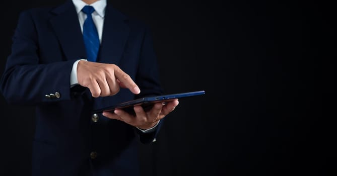 Businessman standing and holding tablet on dark background. Copy space. banner sign