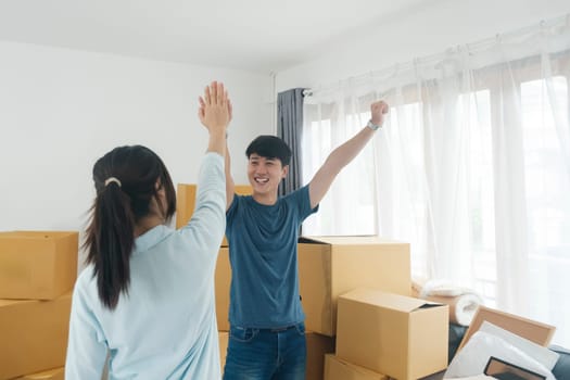 Happy couple with cardboard boxes in new house at moving day. New house owner and real estate concept.