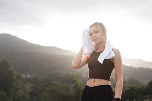 Portrait Young beautiful Asian woman wiping sweat after evening jogging in the park..