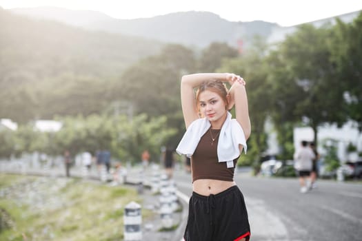 Portrait of sporty and happy young Asian woman in sportswear stretching arms Warm up before heading out for an evening run in the park..