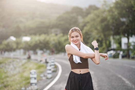 Portrait of sporty and happy young Asian woman in sportswear stretching arms Warm up before heading out for an evening run in the park..