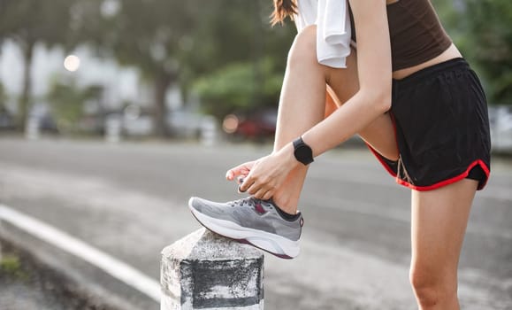 Portrait of a young woman tying her shoes to prepare for exercise..