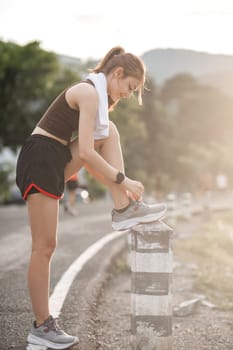 Portrait of a young woman tying her shoes to prepare for exercise..